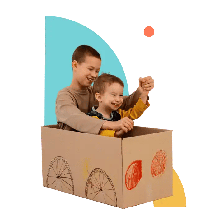 Two brothers playing joyfully in a cardboard car during a behavioural therapy session, supporting creativity and social connection for children with autism