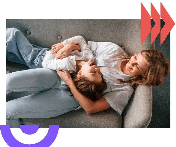 Mother and child sitting closely on a couch, sharing a warm, supportive moment in family therapy under the NDIS framework.