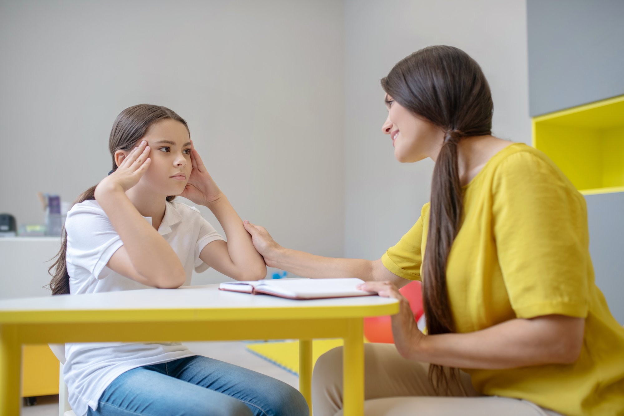 helping-hand-sad-girl-school-age-sitting-table-attentive-kind-woman-psychologist-touching-her-hand