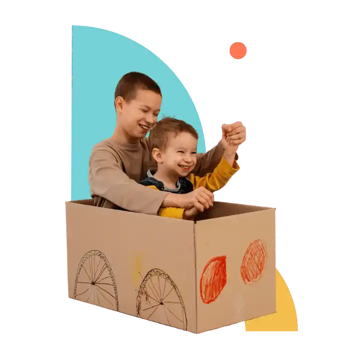 Two brothers playing joyfully in a cardboard car during a behavioural therapy session, supporting creativity and social connection for children with autism